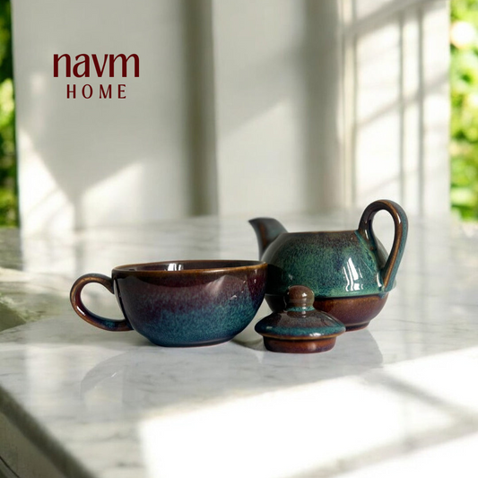 A stackable ceramic kettle and cup set with a green and brown color scheme, placed on a marble surface with a blurred background.