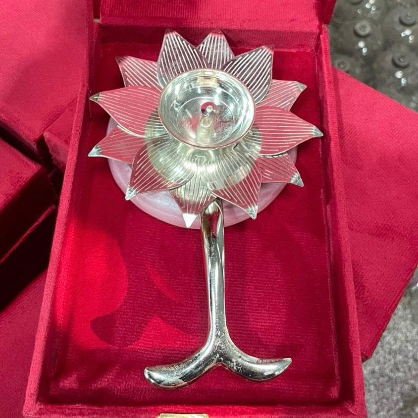 A silver-toned flower-shaped candle holder with a stem and three petals, displayed inside an open red velvet presentation box.